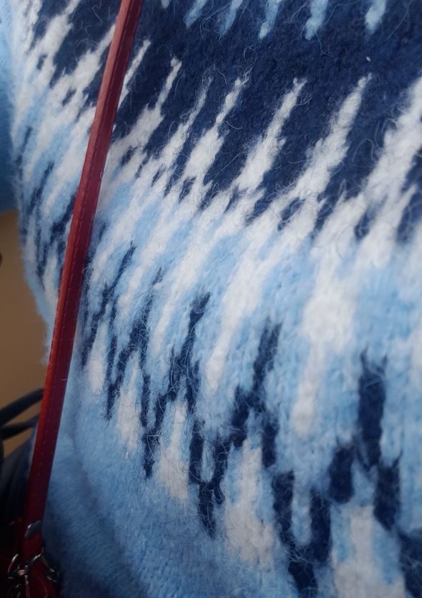 partial view of blue fairisle jumper and red bag strap