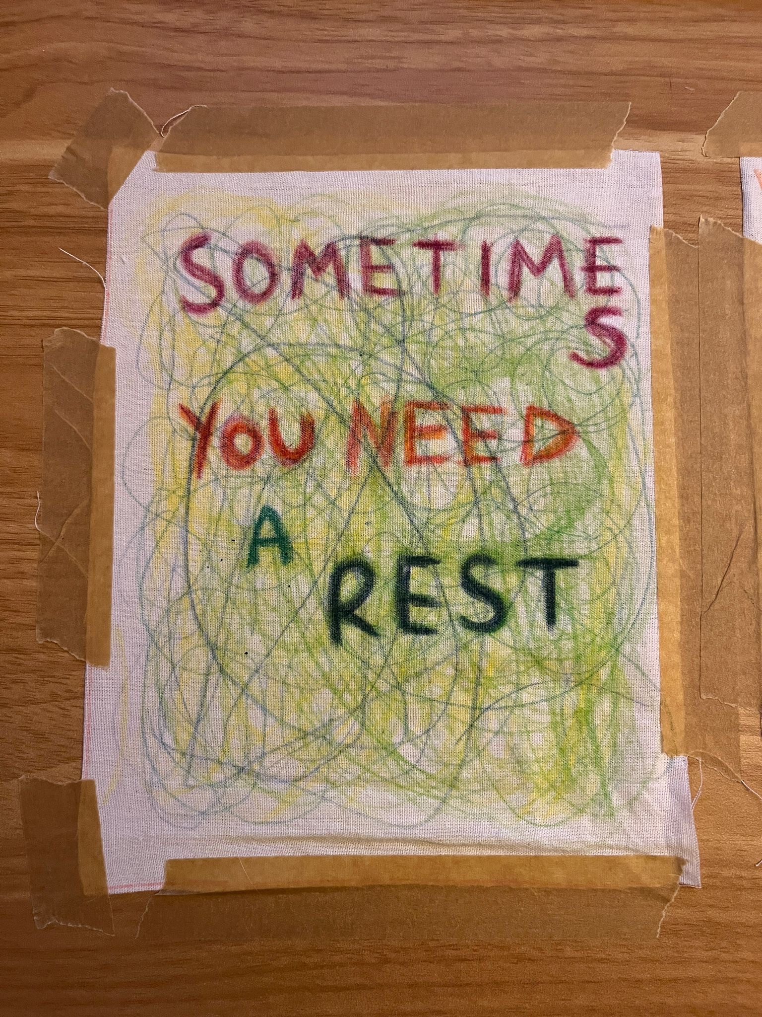 Pencils on fabric spelling “sometimes you need a rest” with scribbles in the background