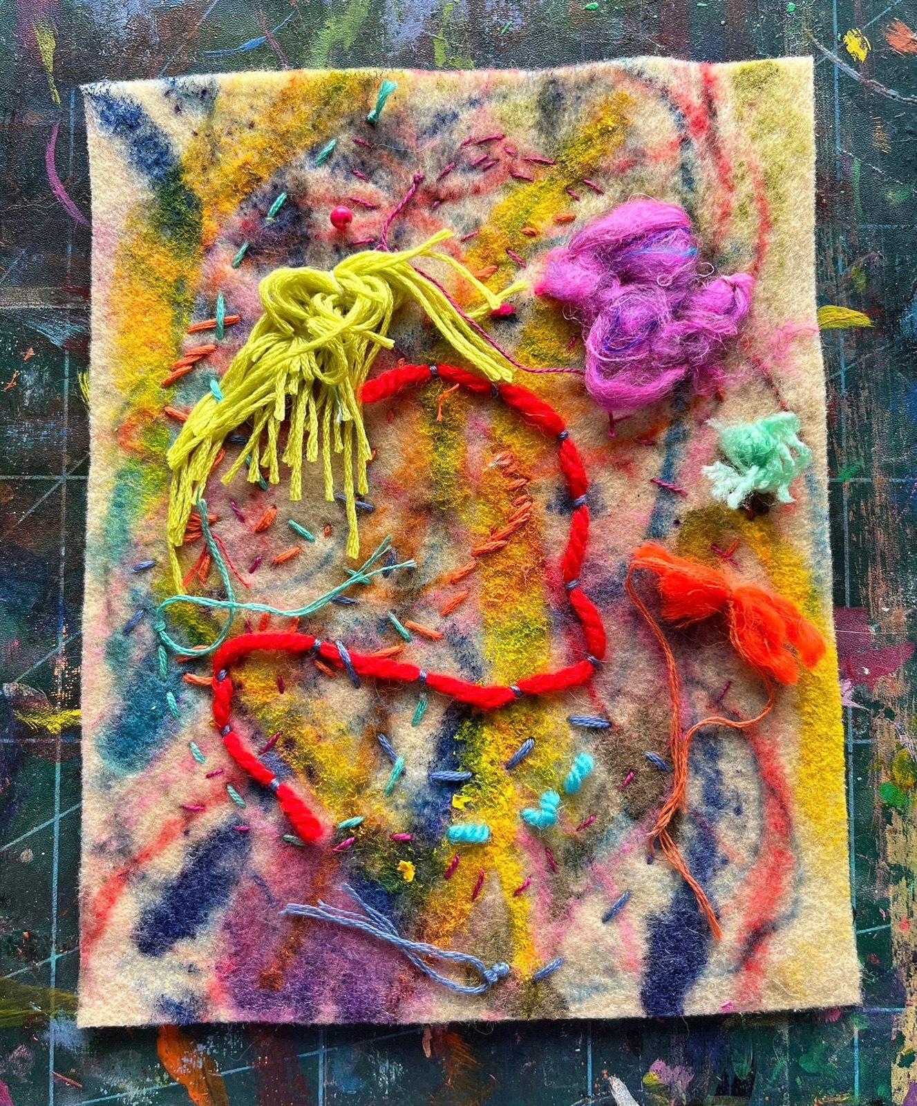 Felt decorated in colourful paint marks, with couched thread and yarn