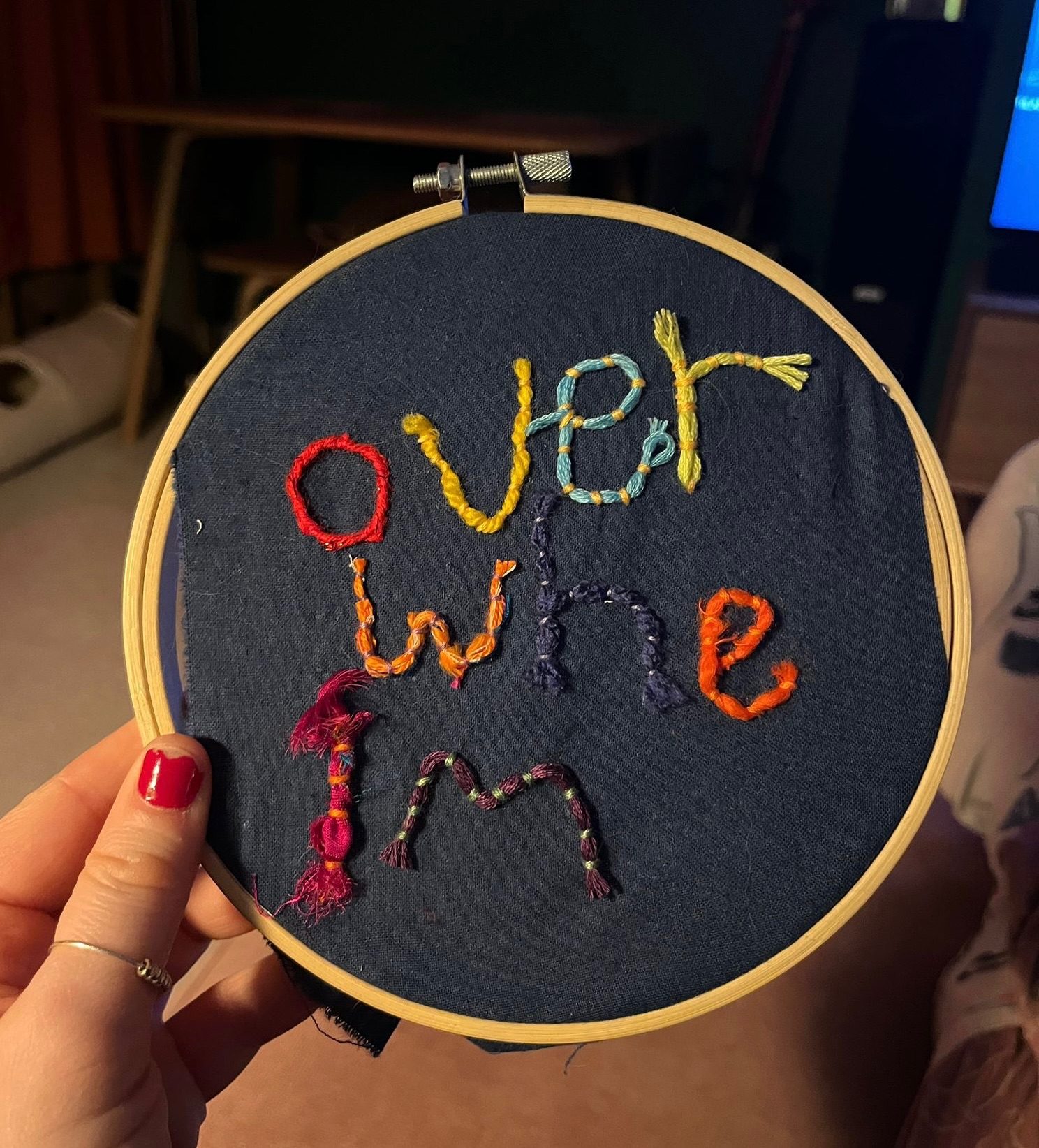 Stitched letters spelling “overwhelm” on a dark blue background