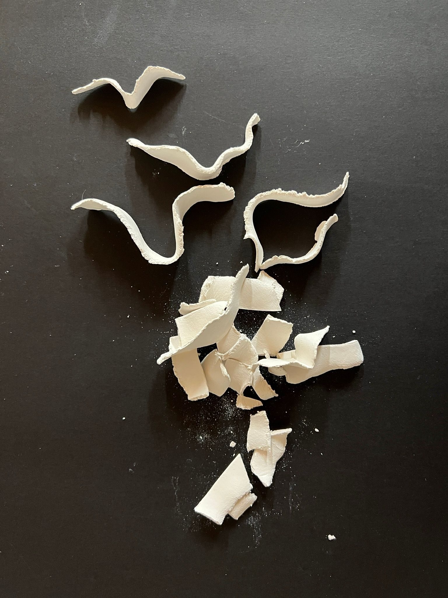 Small broken porcelain fragments arranged on a black surface