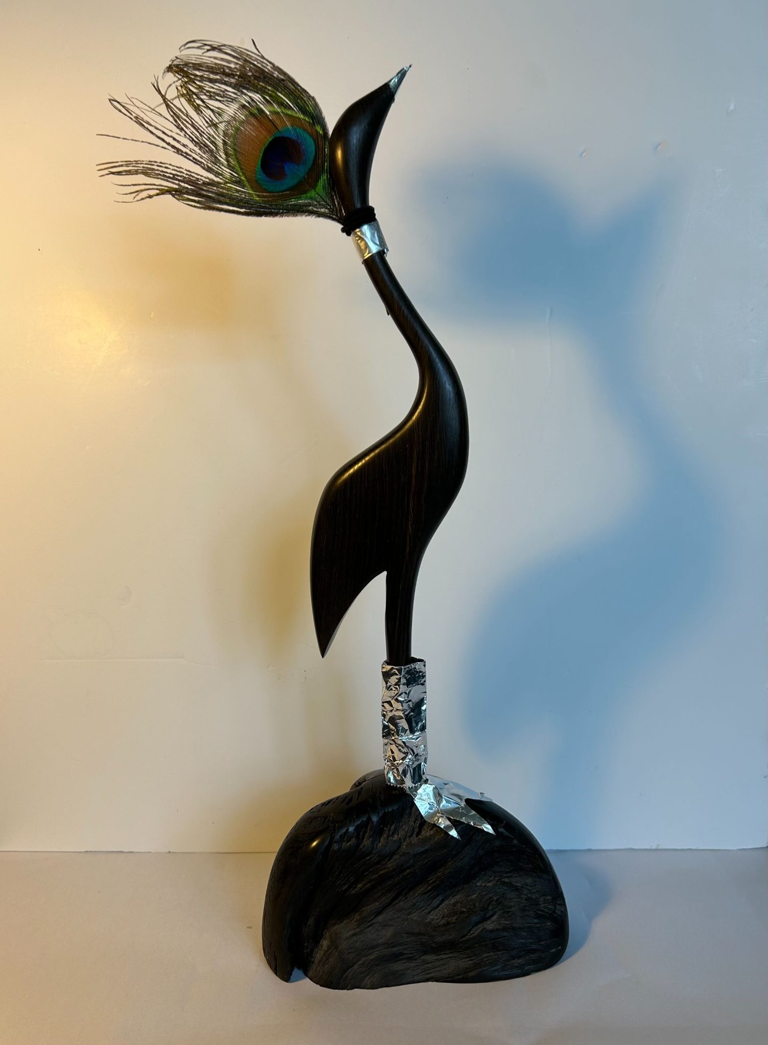 Bird sculpture gets a make over with a new hat made from one peacock feather and wellington boots made from silver tin foil paper