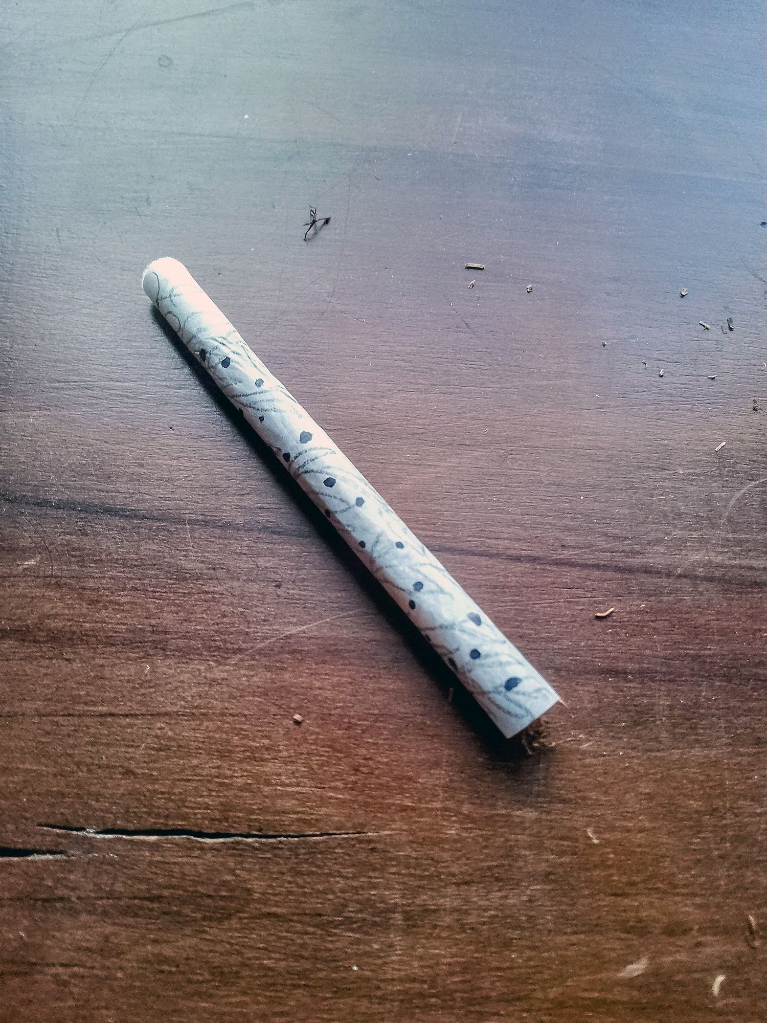 Rolled cigarette in hand decorated paper with pencil and black marker