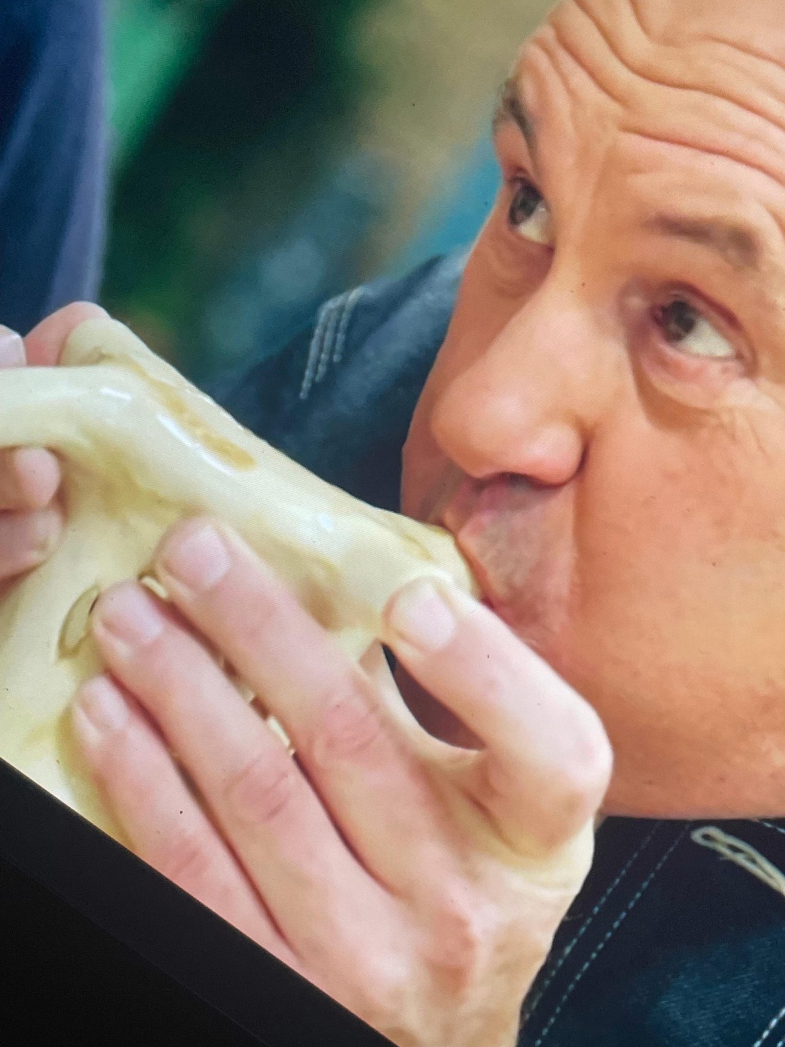 A photo of a guy from the programme the great pottery throw down. He’s blowing into a ceramic pot.