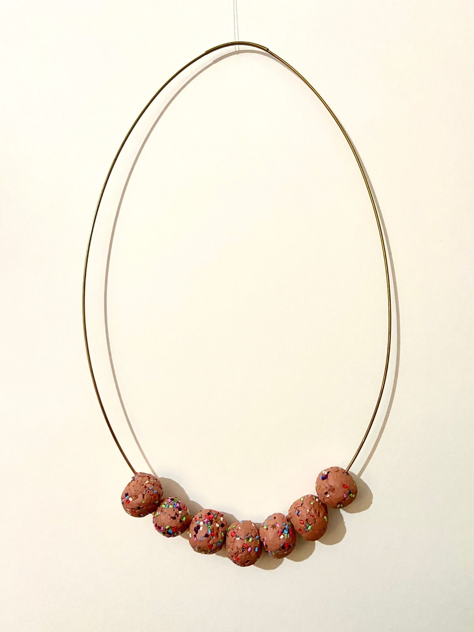 brass rod formed into an egg shape, holding 7 clay balls with beads