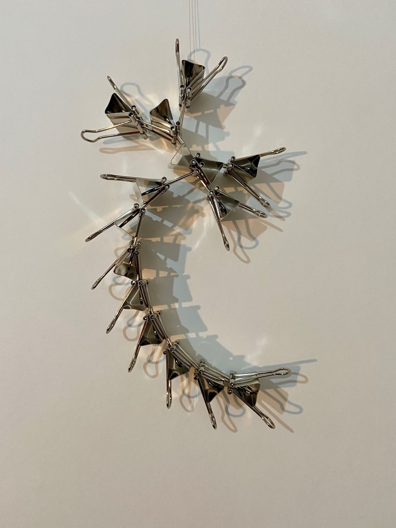 14 bulldog clips held together, showing their shadows