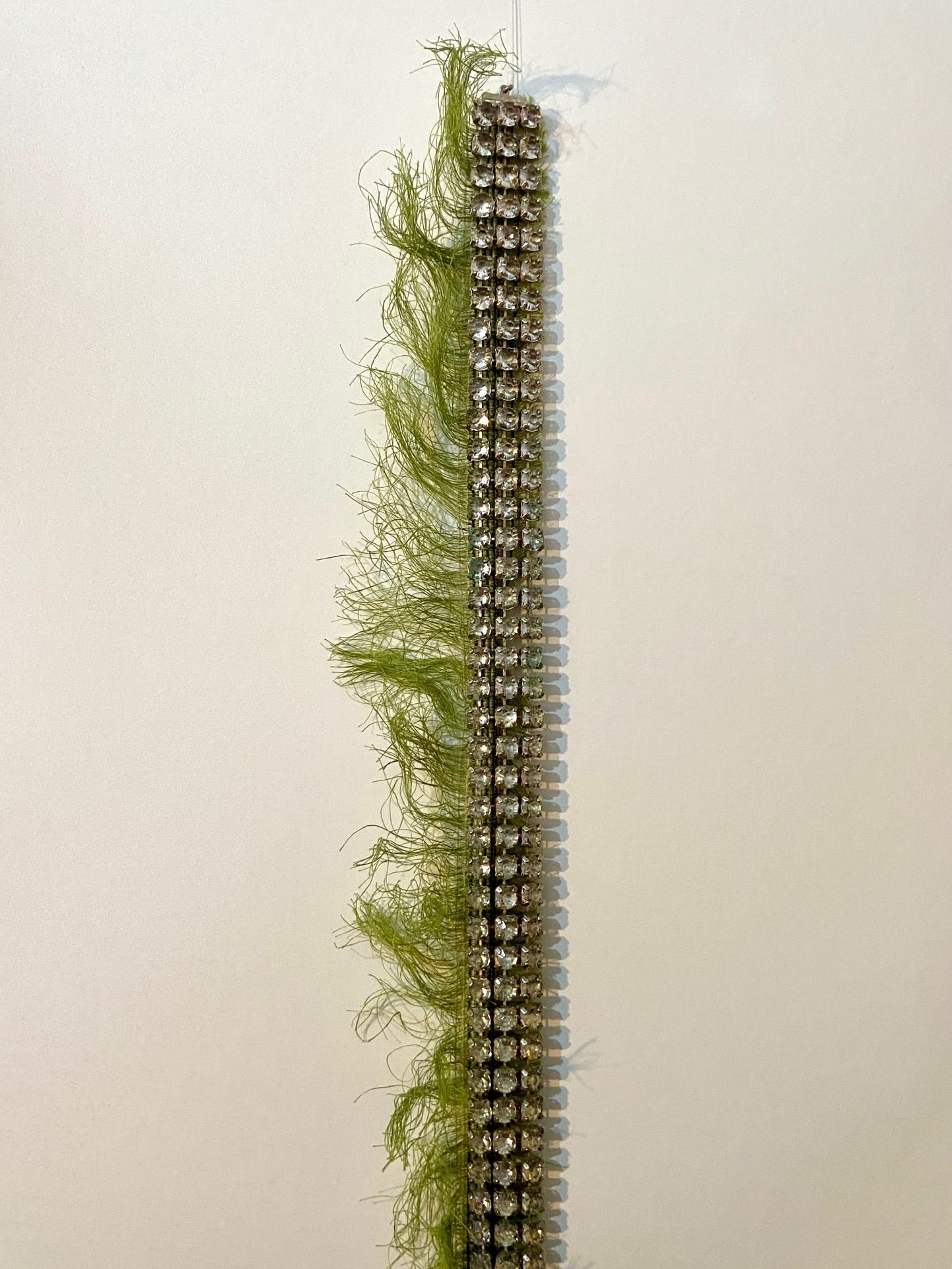 a diamond belt, laid over green hairy textile that smells of sheep