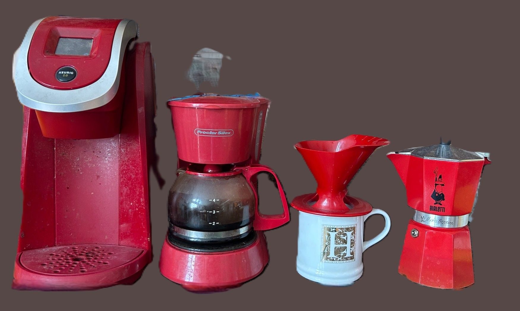 four different red coffee makers lined up on the counter