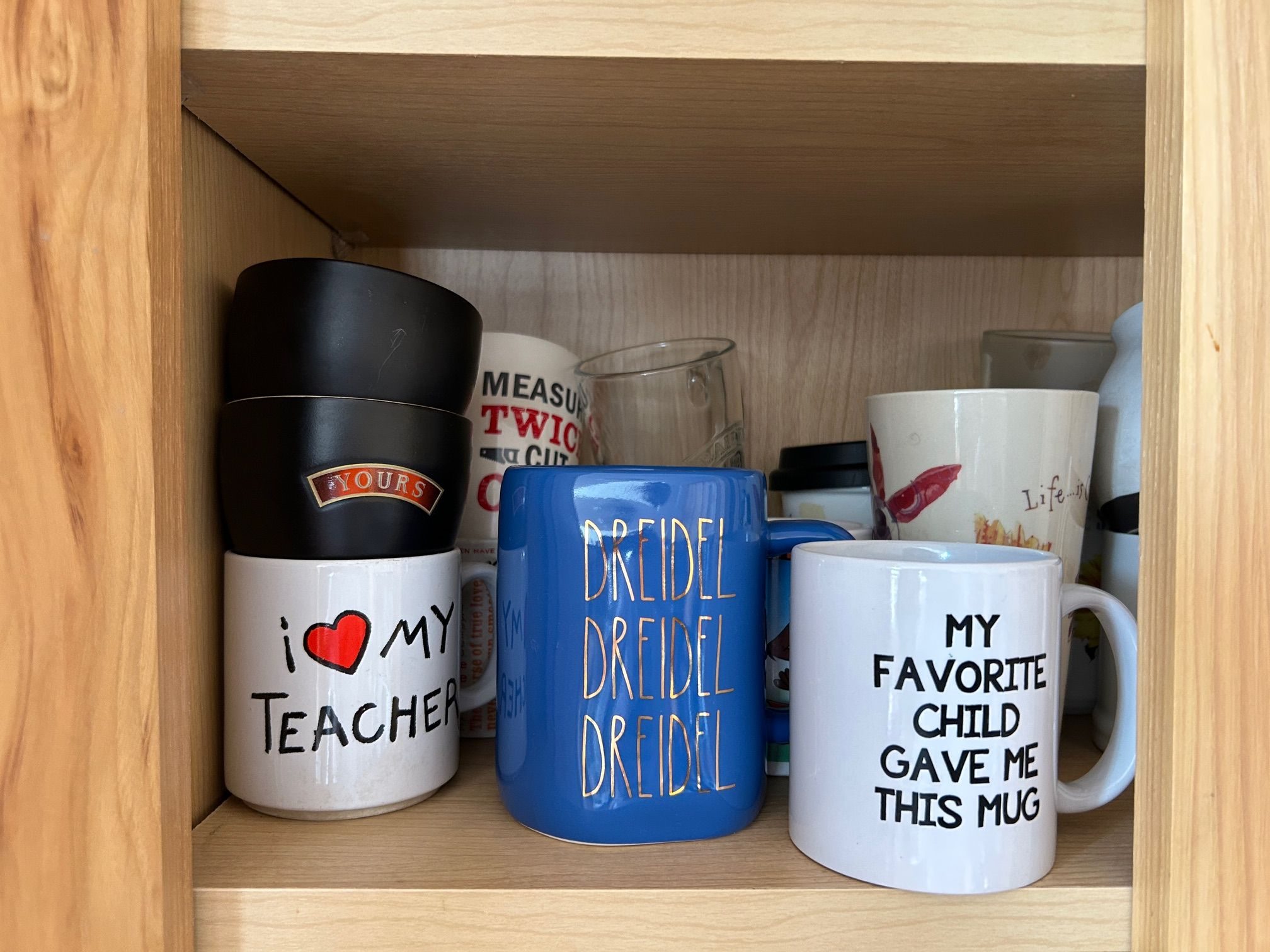a shelf of mugs with each saying on the mug revealing something about me