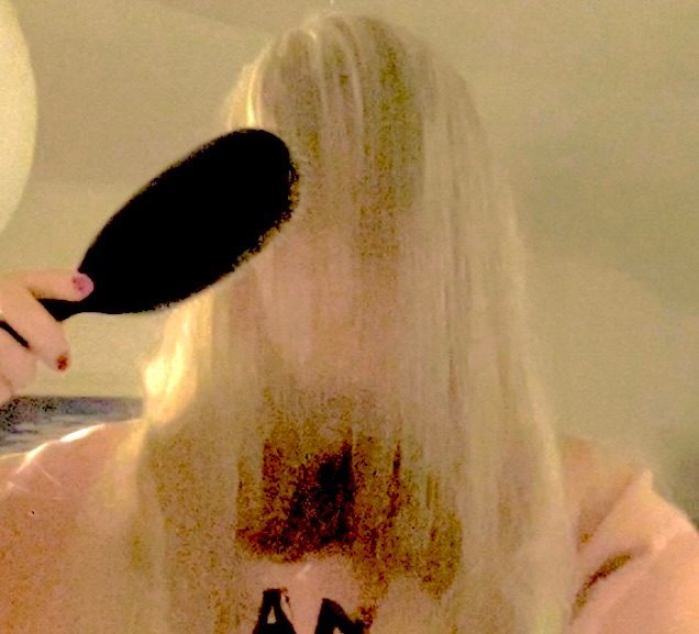 Over-exposed image of artist brushing her hair from back to front