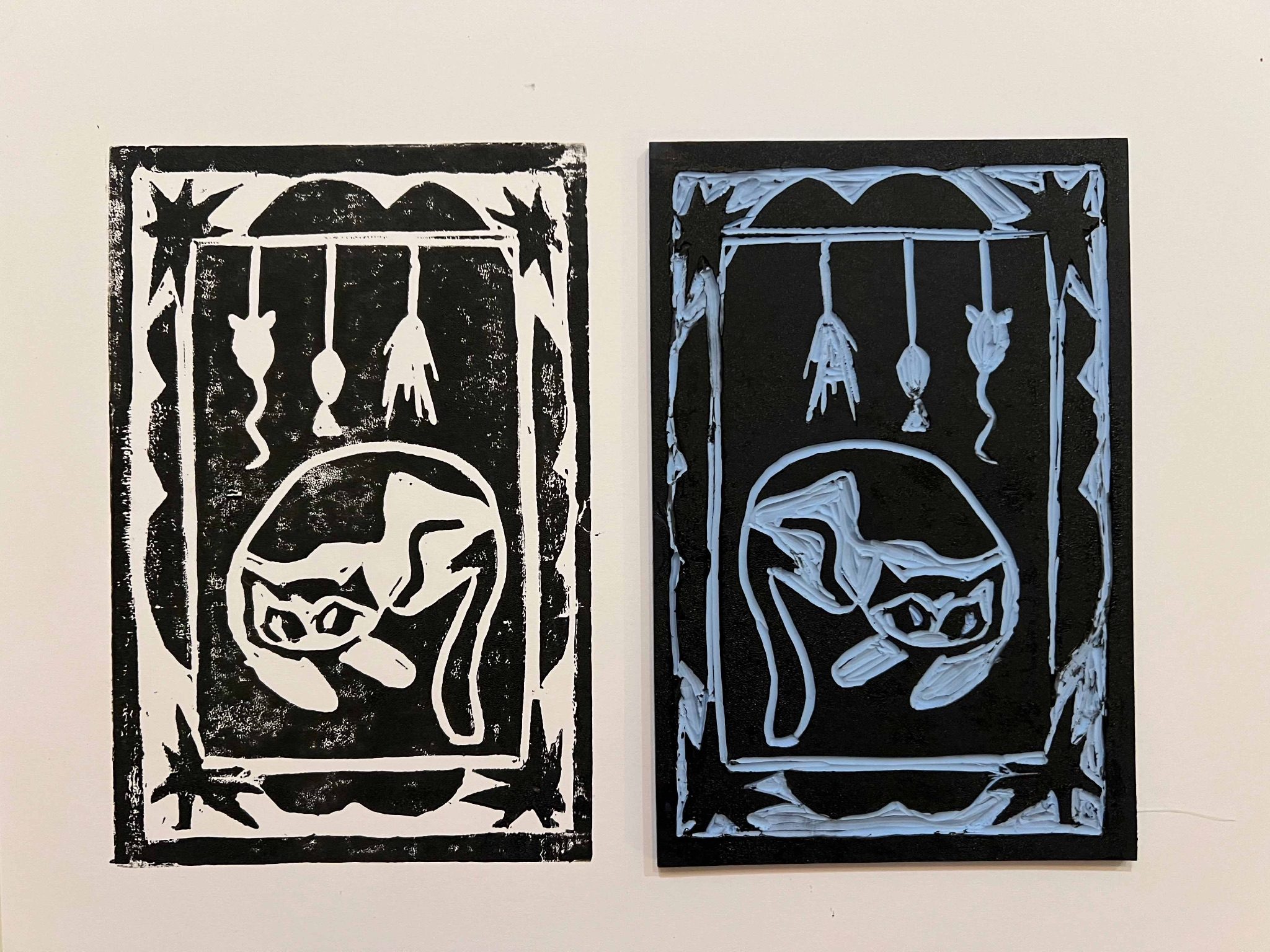 Lino cut print of a cat laying underneath some cat toys with a starry border.
