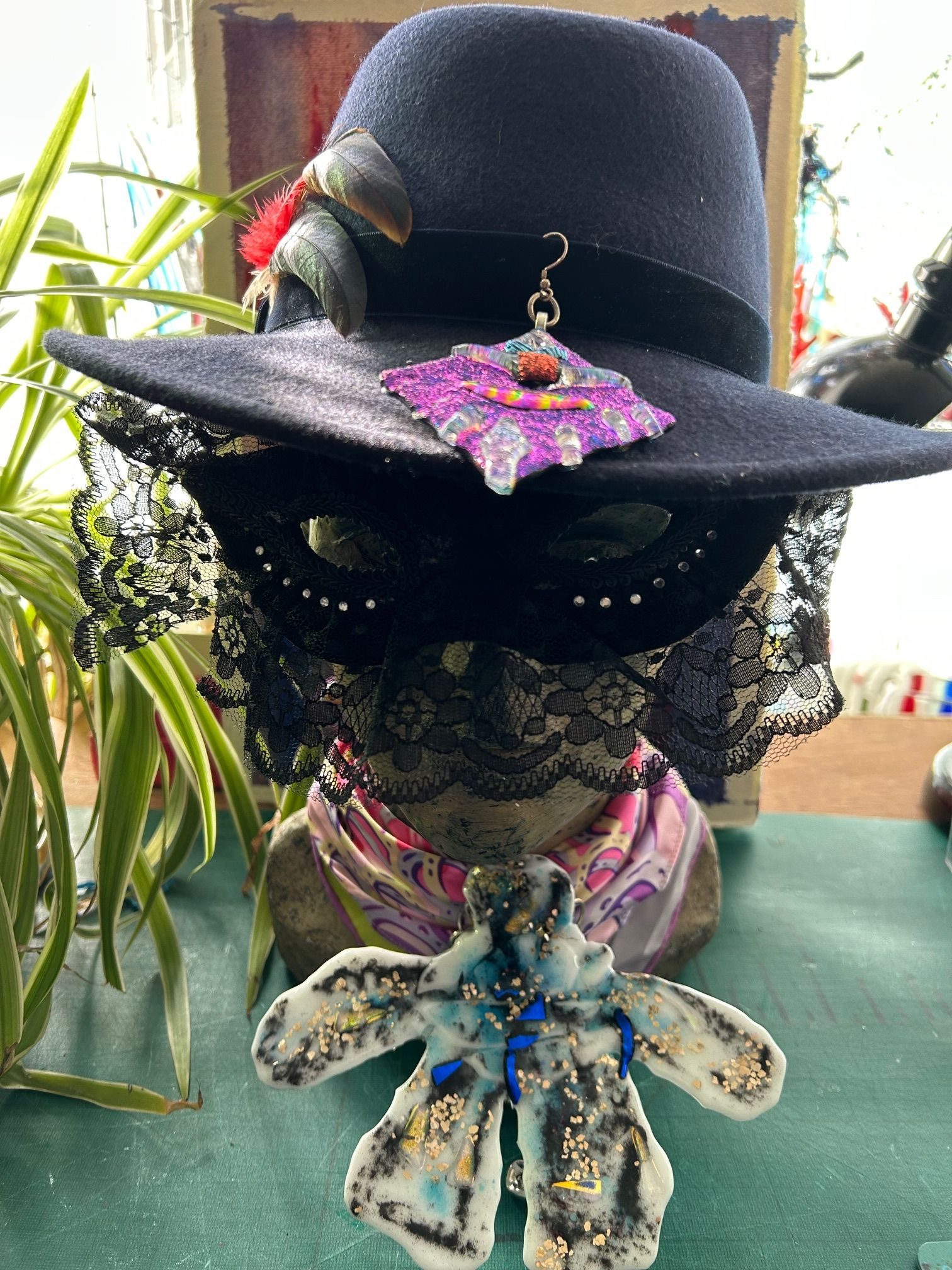 A sculpted woman's head with hat, glass jewellery and black lace mask
