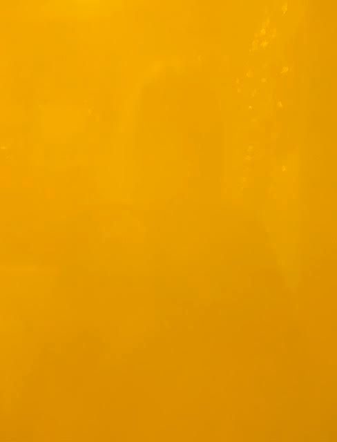 colour photo of indistinct reflection - outline of hair, shoulders - in a shiny egg-yolk yellow surface