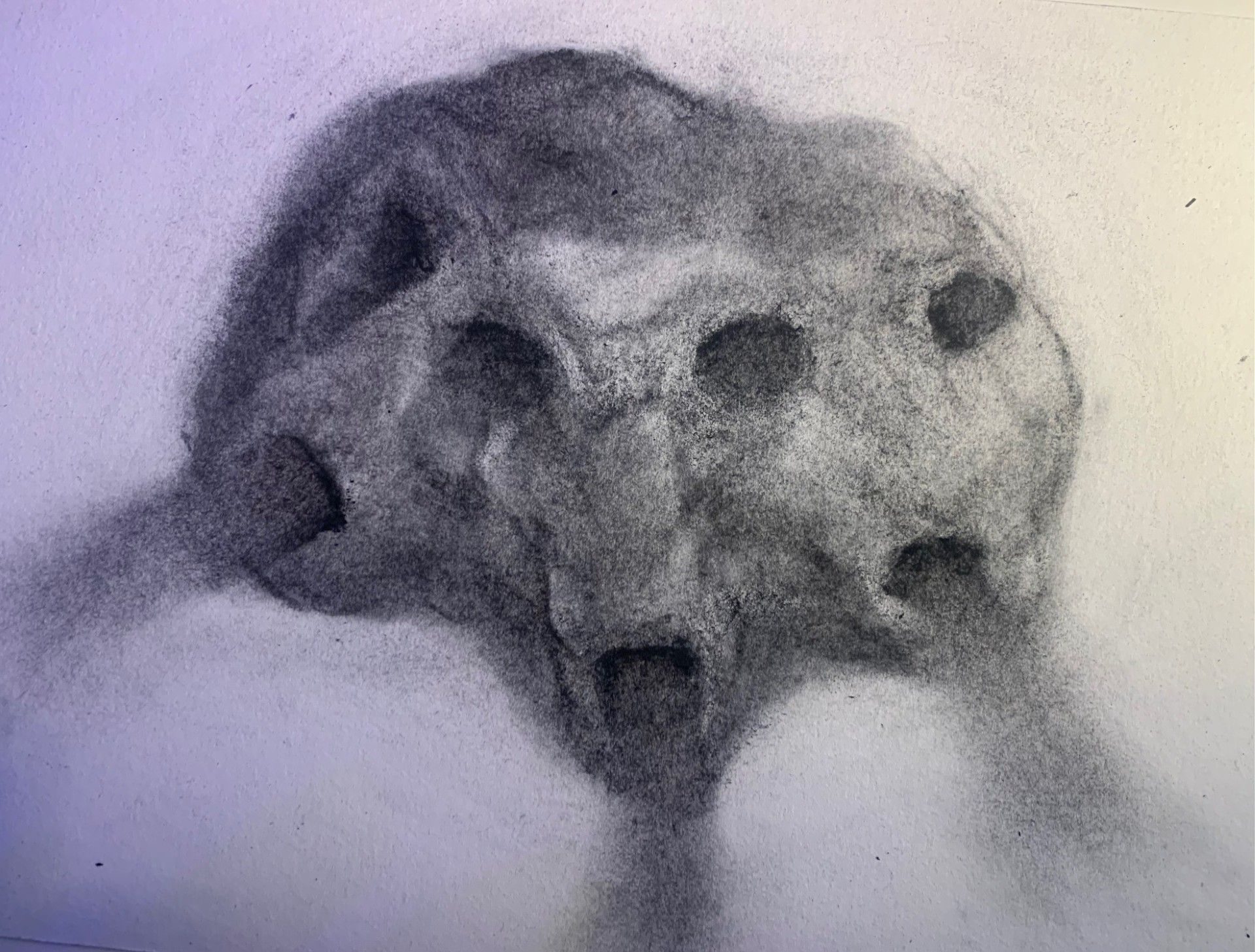 A blurry charcoal drawing of a three faced mask, blowing out air of its mouths