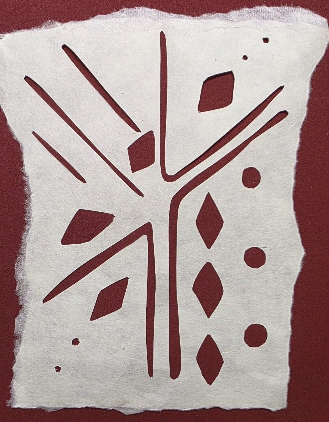 Stencil cut from Japanese Washi Paper, stylised lines, diamonds and circles, laid on textured red paper.