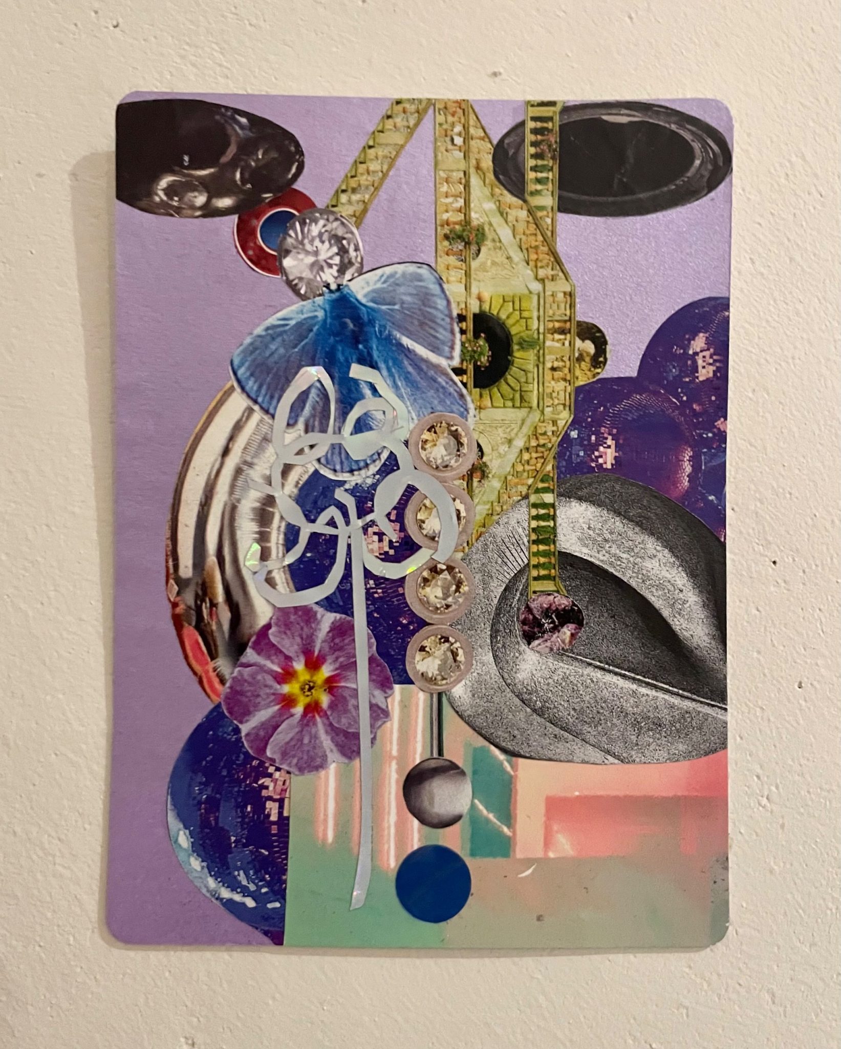 Collage on metallic card with overlayed imagery including silver balloon, gems, Italianate garden wall, butterfly, two big dark ovals at the top like shadowy eyes