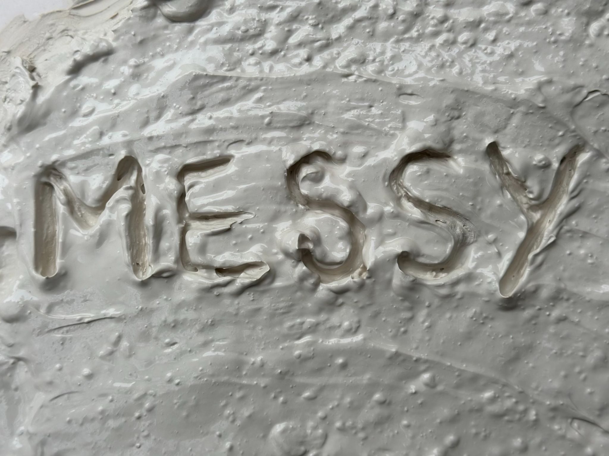 The word 'messy' written into porcelain reclaim clay