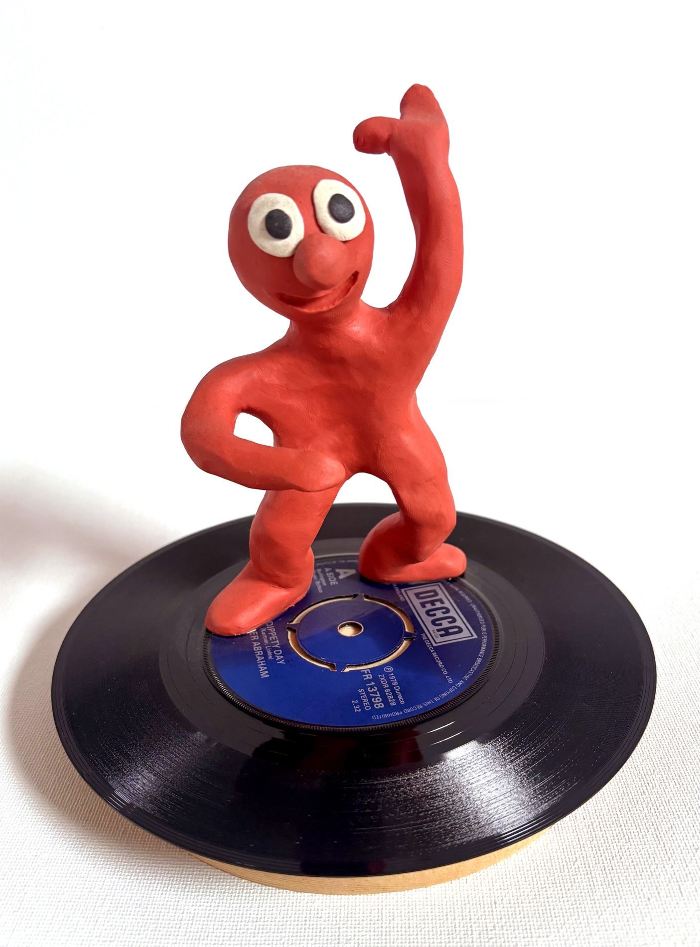 Plasticine sculpt of Morph stood on a record.