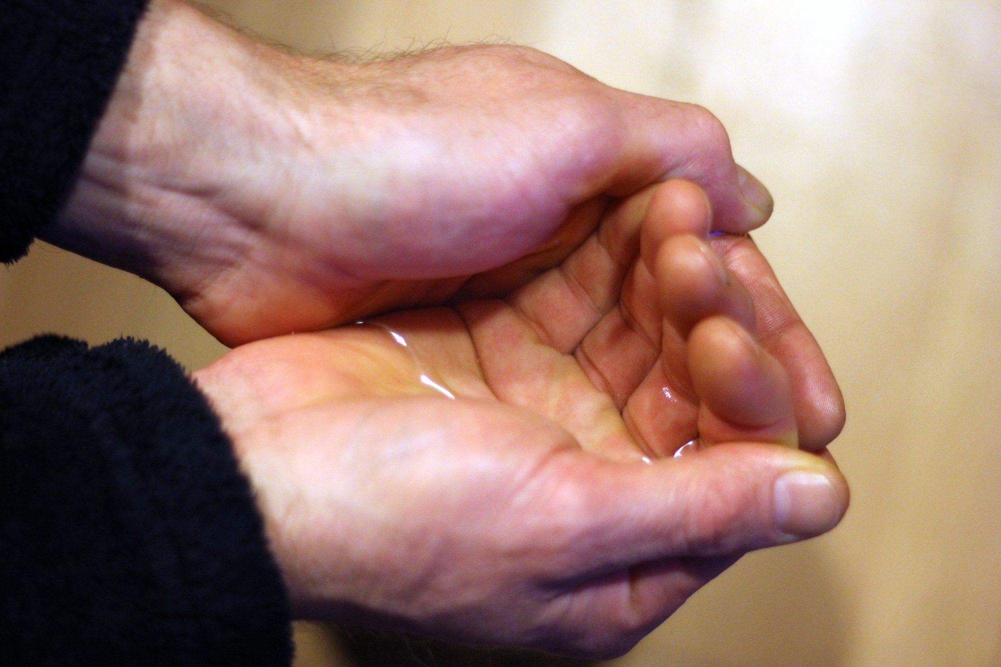 Two hands cup together to hold a pool of water.