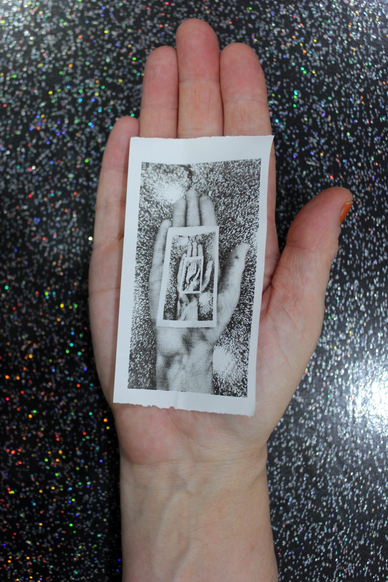 A hand holds a printed image, that is of the hand holding a printed image, that is of the hand holding a printed image, that is of the hand holding a printed image.