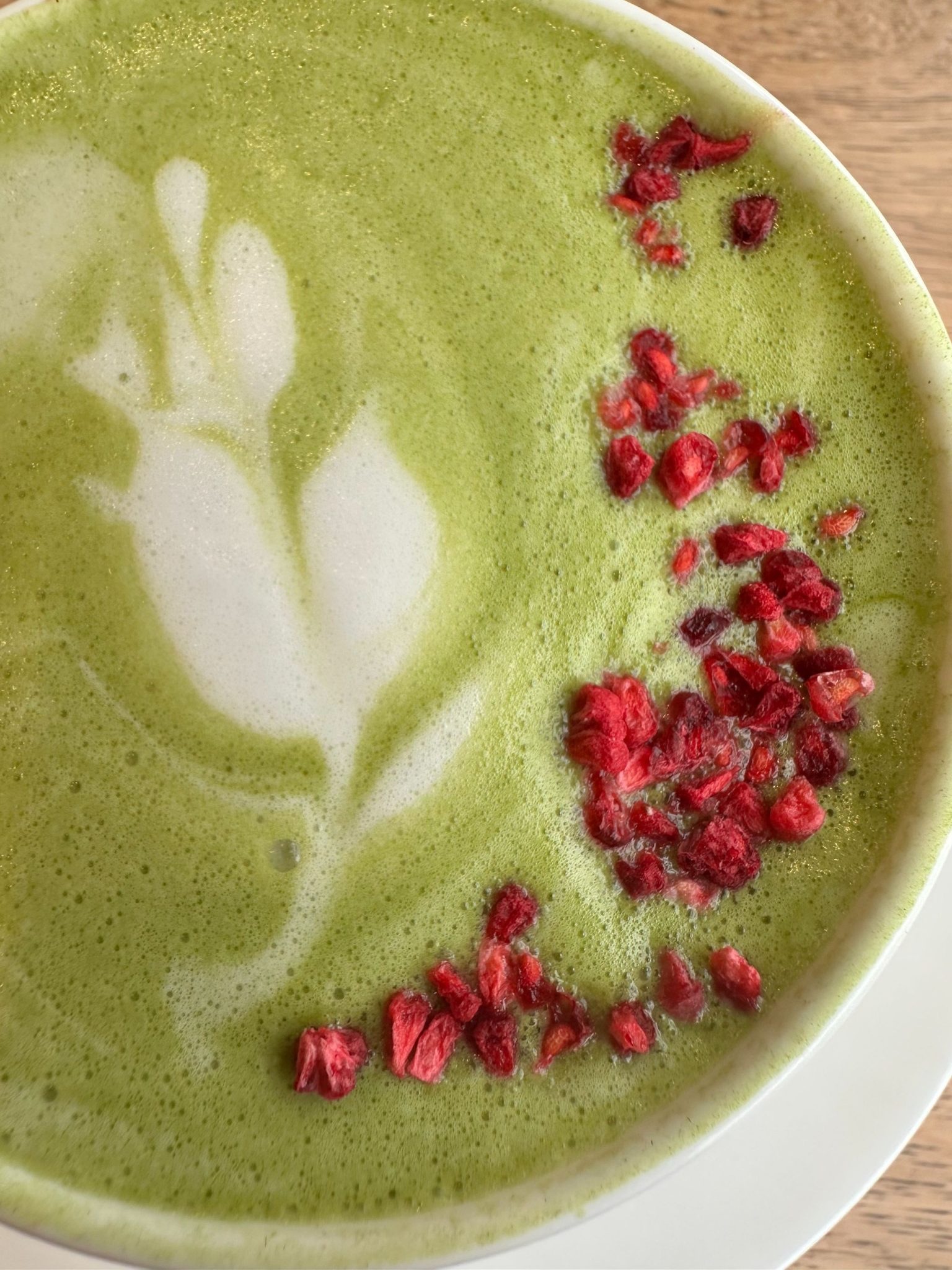 Photograph of Matcha Latter  froth in shape of a flower with Freeze Dried Raspberrys