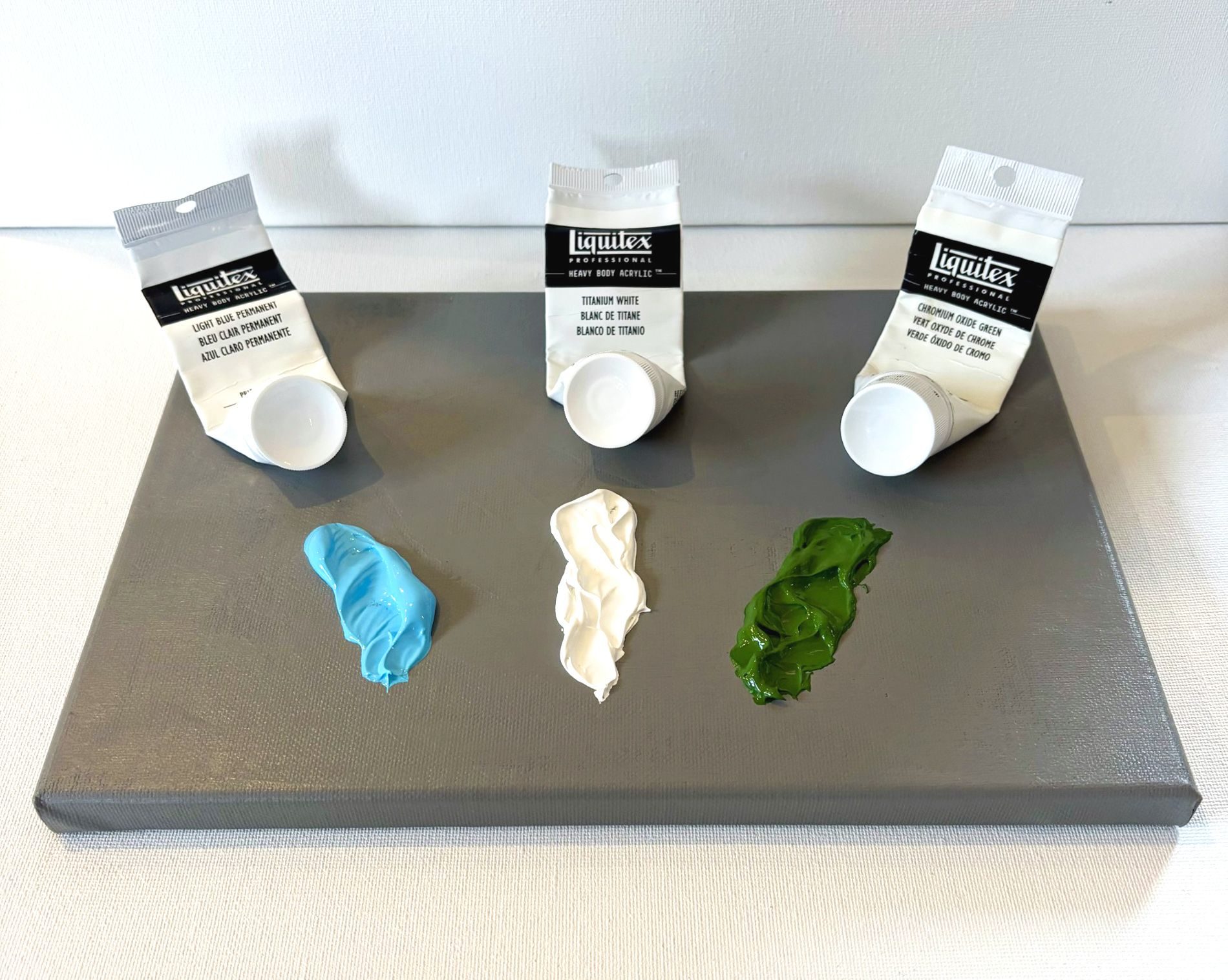 Three tubes of acrylic paint which have almost been completely used.