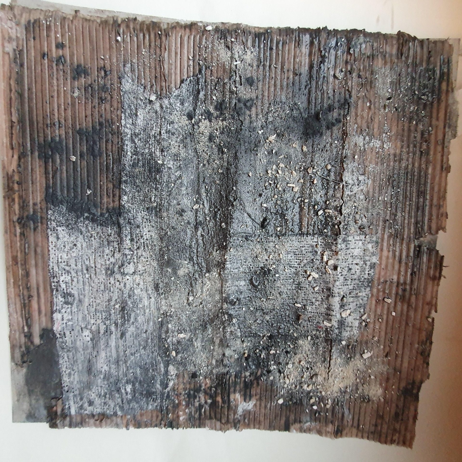 Remains of a wall made with recycled material on top plaster, graphite, pvc, ashes and water