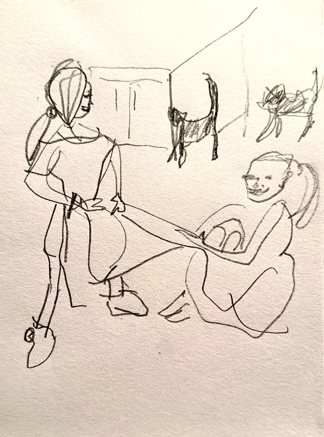 Two children pulling a blanket between them, one standing, one sitting and partially wrapped in the blanket. Two cats in the background.