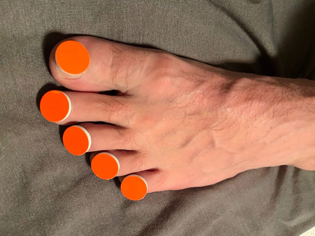 A foot with small orange discs on the nails
