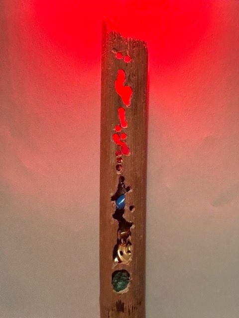 Hollow stalk with holes cut into it so you get glimpses of bits and bobs inside- buttons and beads lit from above with a red light