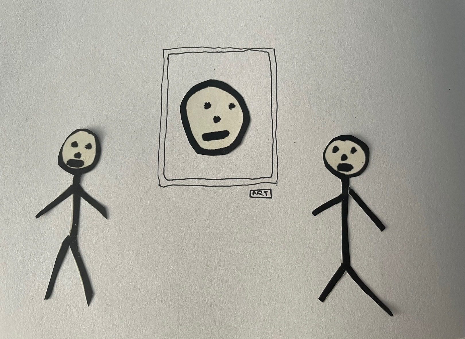 To cut out images of black-and-white stick man either side of a wobbly drawn frame with a stick head in it. Underneath the frame is a tag that says art.