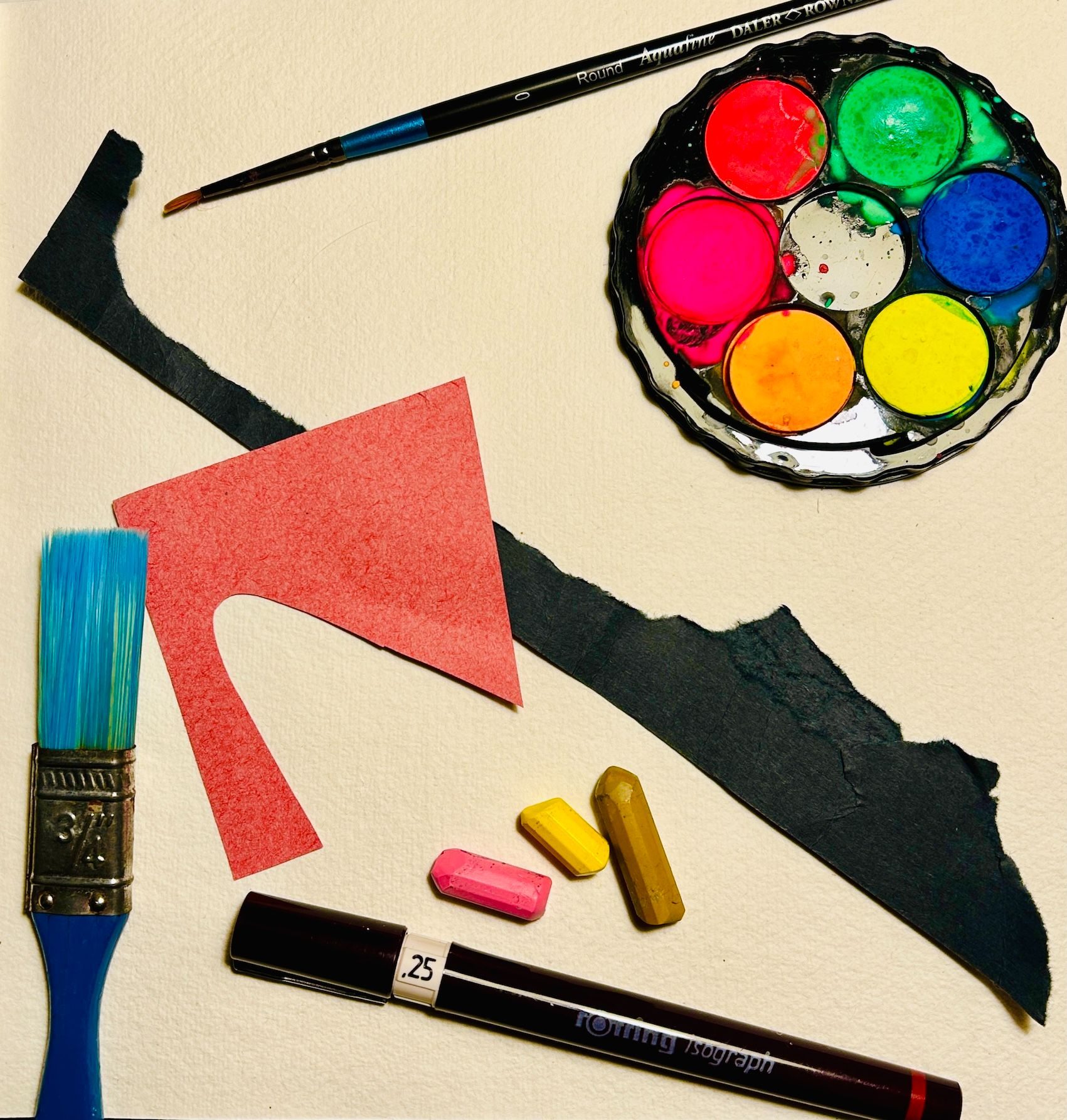 Art materials and equipment arranged in a square piece of watercolour paper