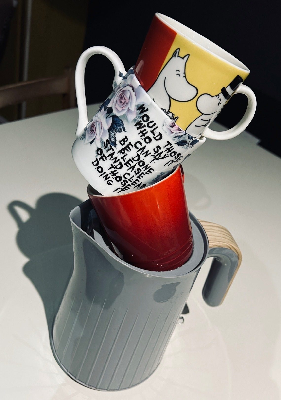 Three mugs stacked on top of a kettle