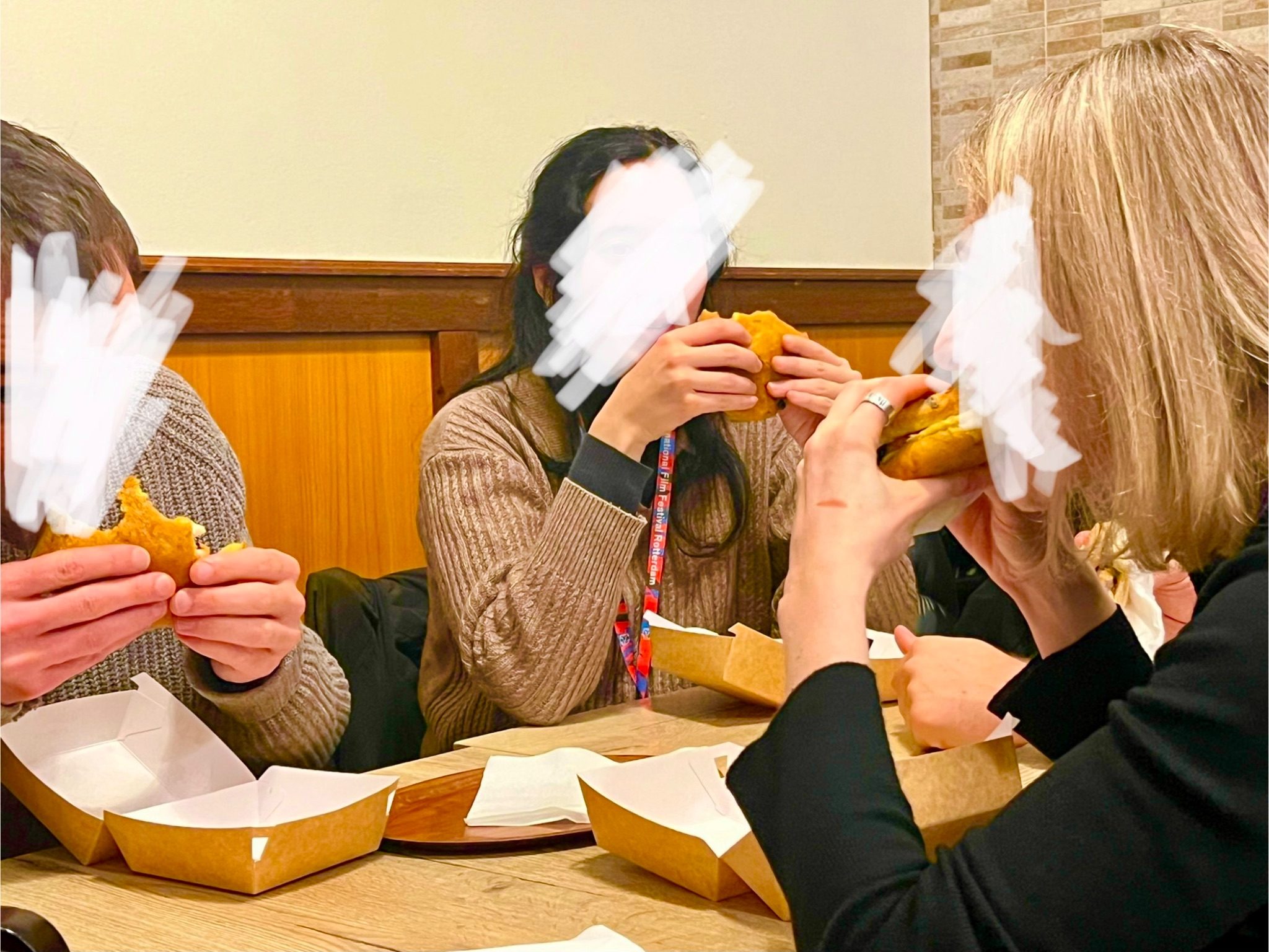Three people eating bara buns with their faces scribbled out