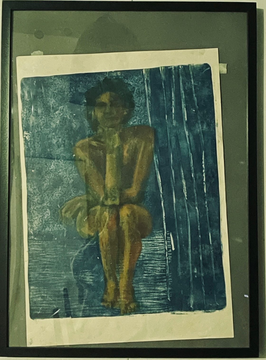 A painting of a naked lady sitting with her elbow on her knee, chin on hand, has slipped out of position in the frame so you can see the masking tape that used to hold it in place.