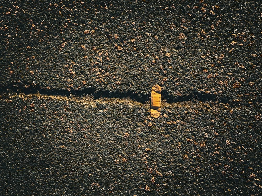 A photo of a plaster stuck on a big crack on an asphalt road