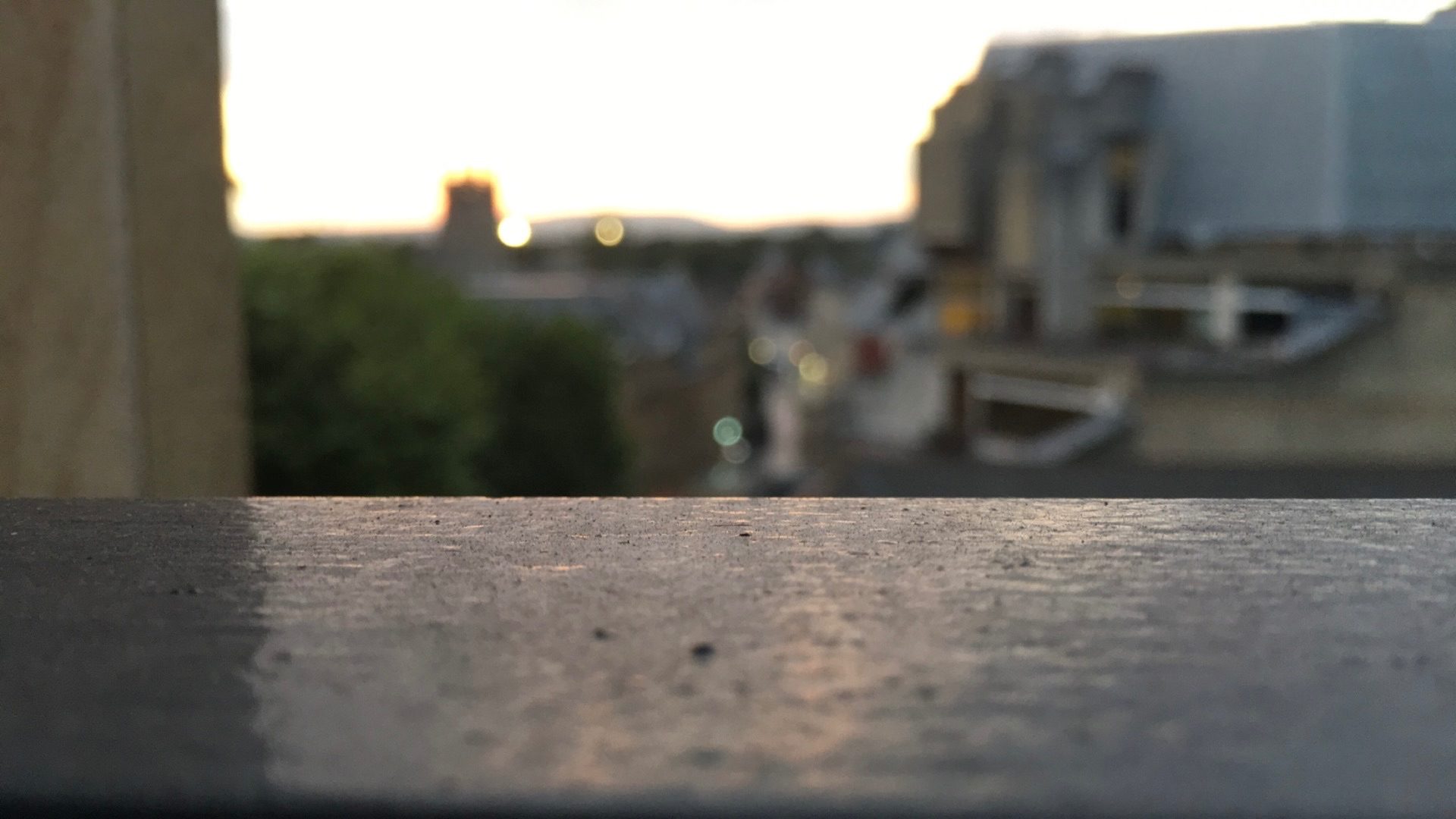 photo of the top of a handrail with the background showing a blurry shot of Cardiff