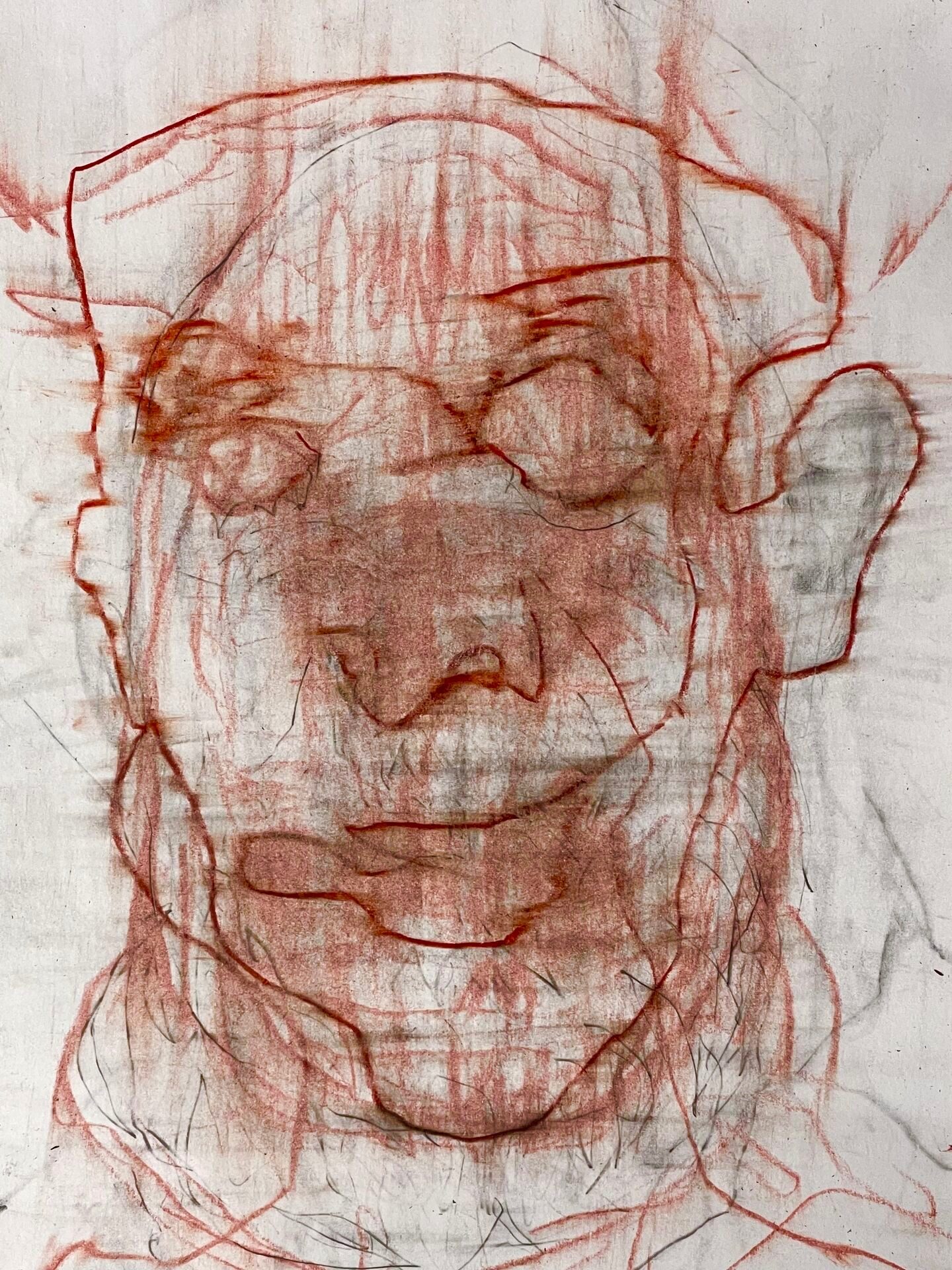 An expressive drawing of a human-like face created with red and graphite pencils. The features are weary and simplified, with the eyes firmly closed, conveying a sense of exhaustion or deep meditation. Frantic, overlapping lines and vertical strokes cut through the face like rain, giving the impression of a figure that is slowly eroding or dissolving into the background. The use of red pigment throughout the composition adds a visceral, strained quality to the atmospheric and scratched texture.