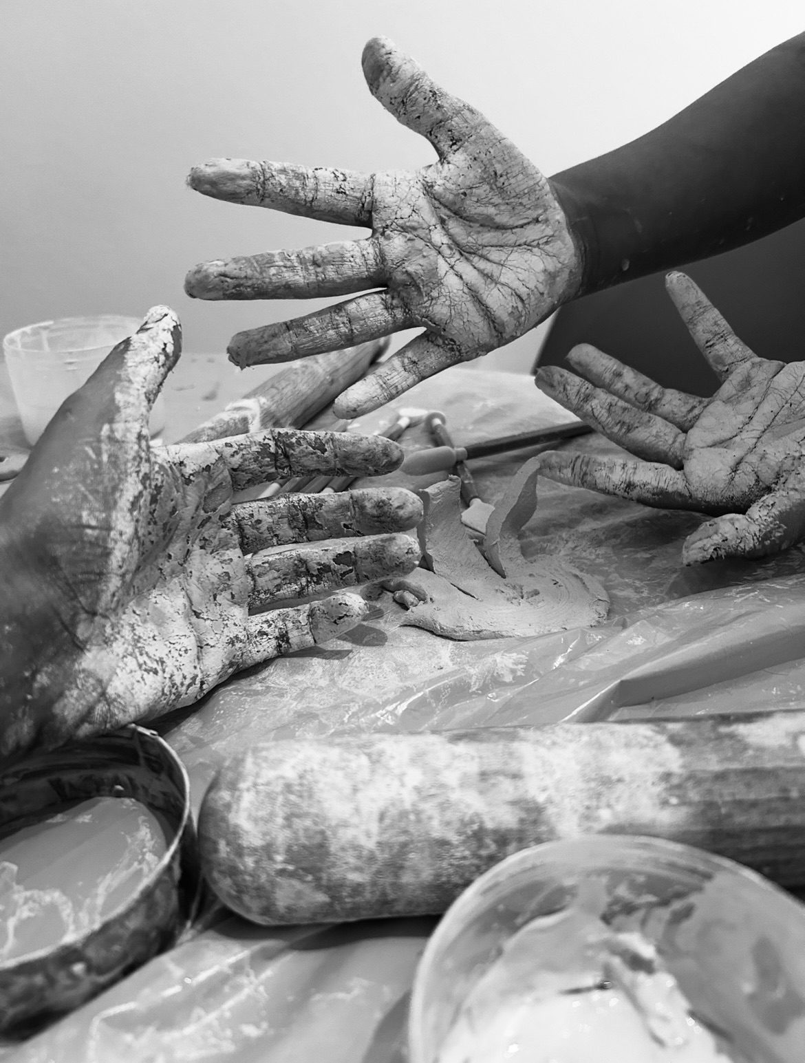 Clay covered hands and sculpture