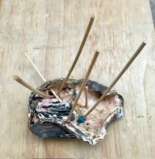 ceramic shell form pierced by wooden spear forms