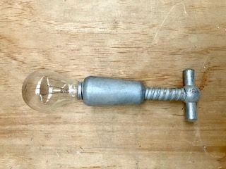 lightbulb fitted exactly into wooden handle of silver painted wooden corkscrew once metal screw removed