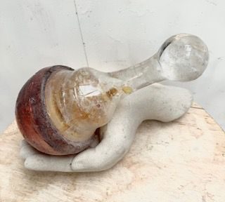 a resin cast dumbell with inset found glass handle held in ceramic hand