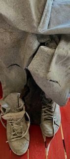 stained studio jeans and boots with piece of ceramic art between