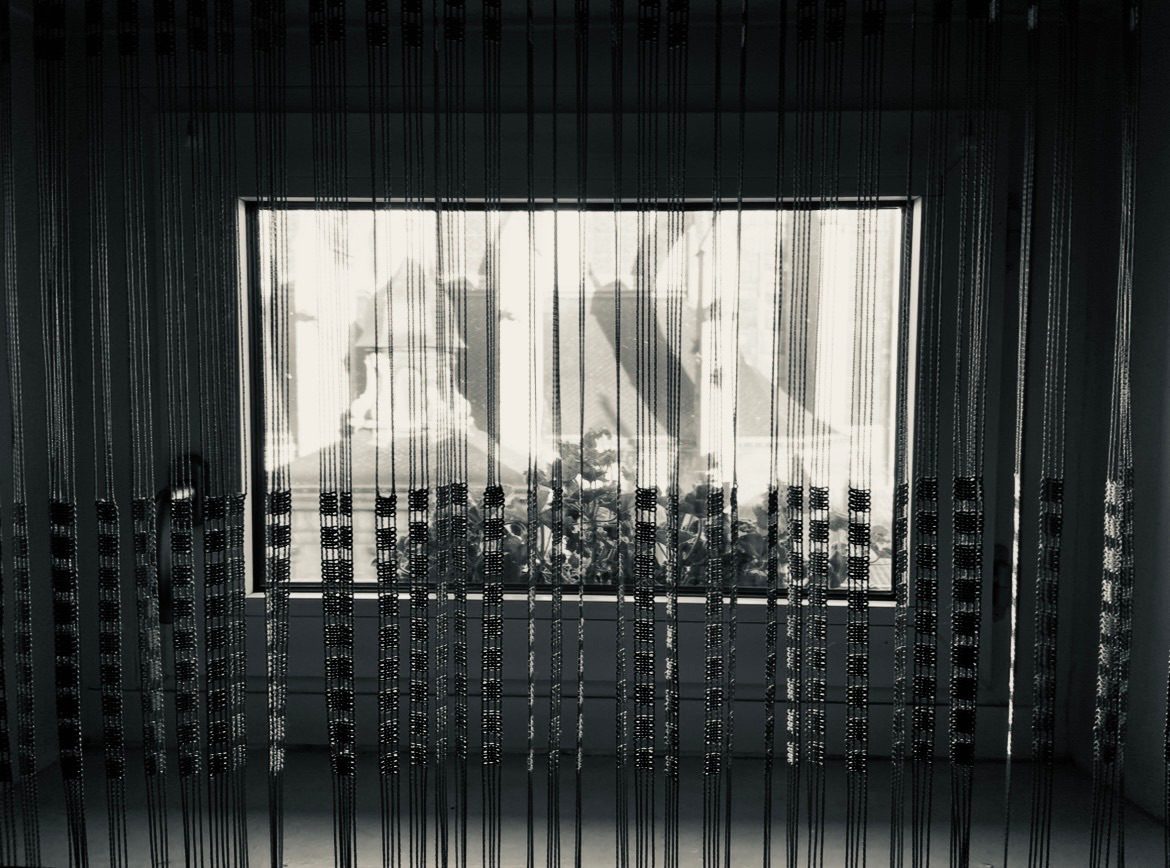 Picture of a small window over looking some plants and a 13th century gothic building