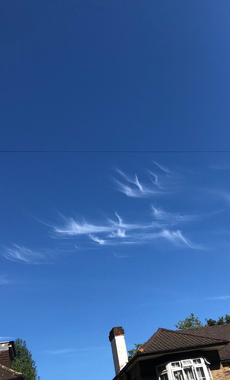 Clouds in an angular and repeating patterns. A thin telecoms wire is running horizontally through it. A little peak of a traditional house is at the bottom.