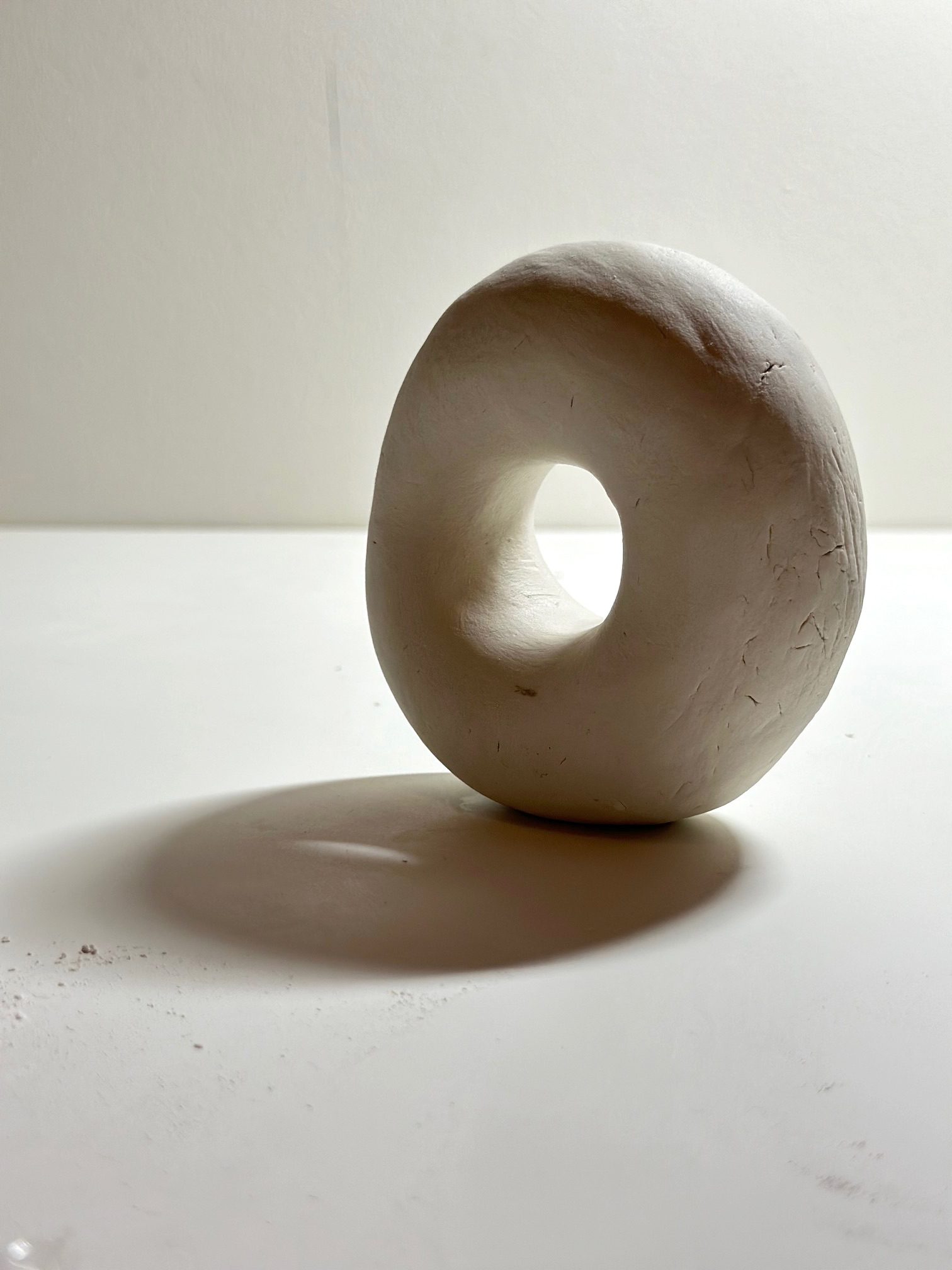 I rolled a small lump of clay that fit in my palm and flattened it slightly, like a rice cake. I pressed the centre with my thumb and index finger, and a hollow began to appear. As I kept pressing, a hole opened. I widened the hole until my thumb could fit inside. The form gradually developed into a ring-like shape.