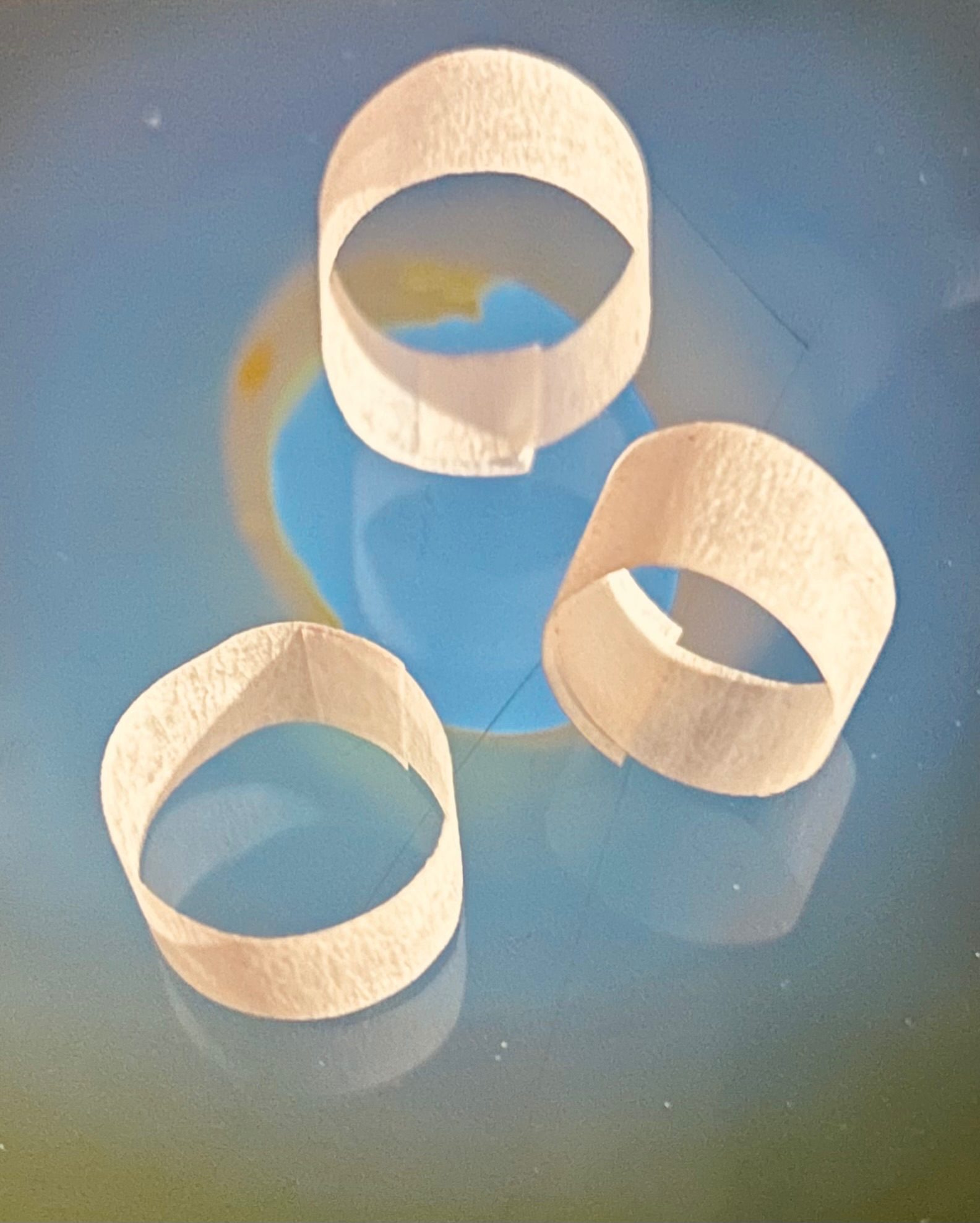 Three narrow masking tape tubes placed on top of an iPhone screen. The bright image on the phone is a close up of a table lamp.
