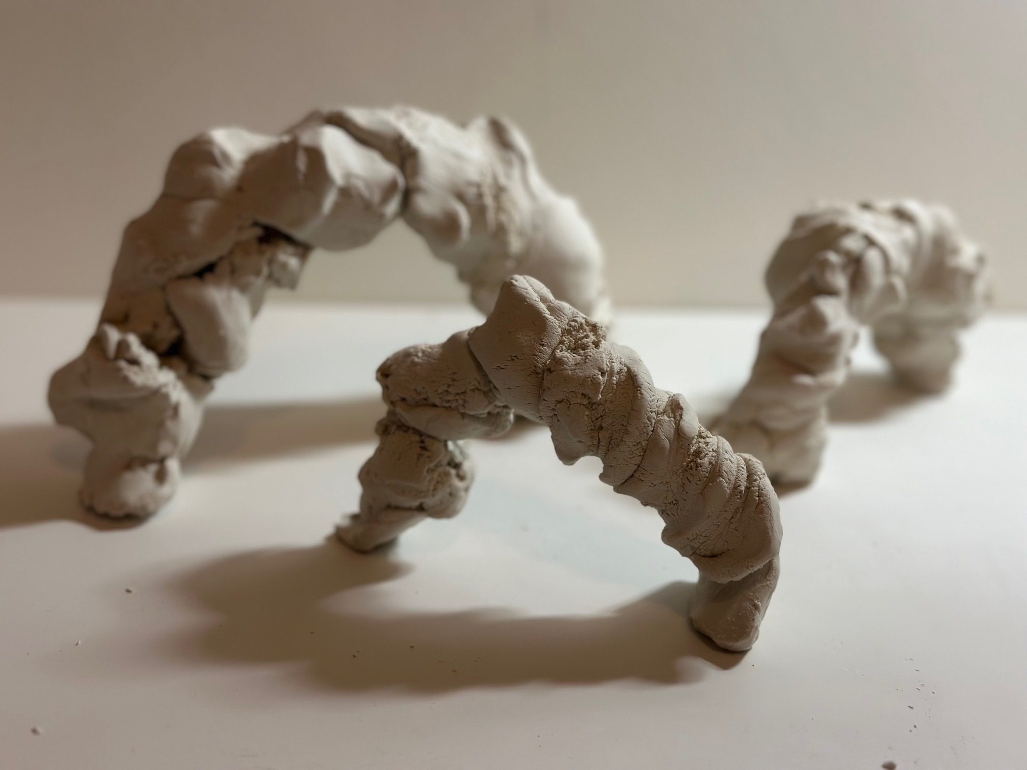 I grasped a mass of clay and twisted it into a large coil. The coil was then lifted and formed into an arch, balancing the form to prevent collapse.