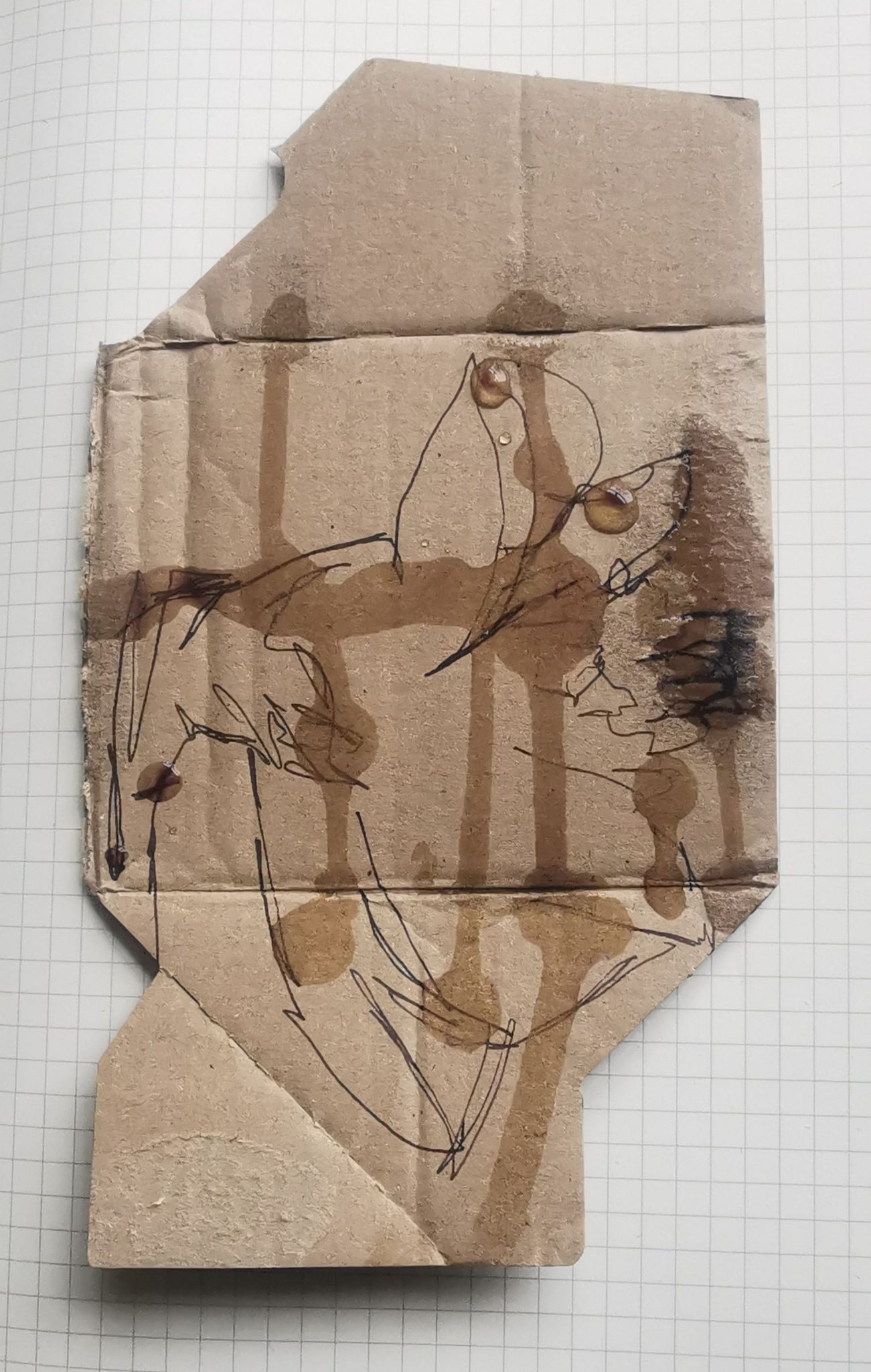 Drawing of a daffodil on a bit of cardboard box, with drops of licorice tea and the articulation if the box to pour back and forth