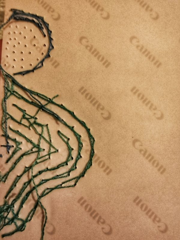 Back of a photograph that has the untidy embroidery stitching.